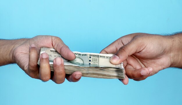 Cropped hands of person holding paper currency against clear blue background