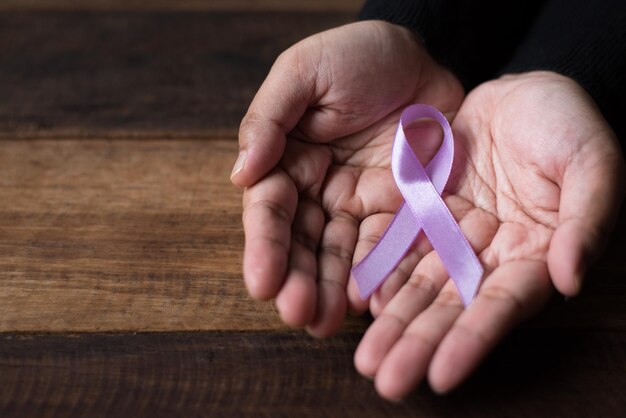 Photo cropped hands of person holding testicular cancer symbol over wooden table