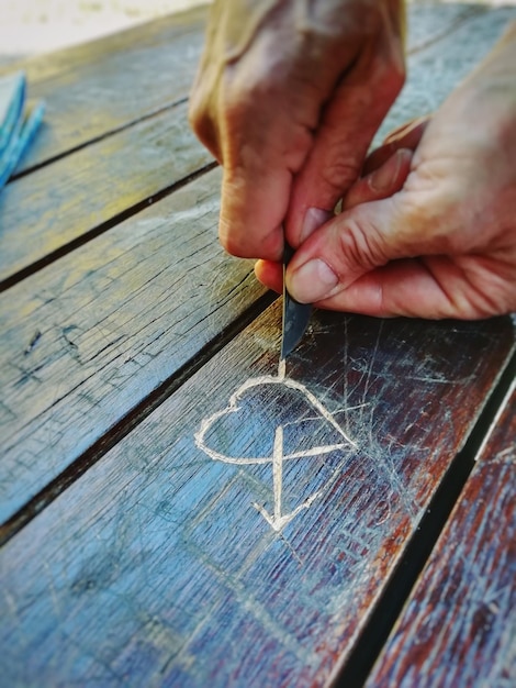 Foto mani tagliate di una persona che fa forma di cuore su un tavolo di legno