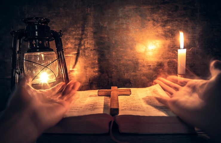 Photo cropped hands of person praying on bible and religious cross