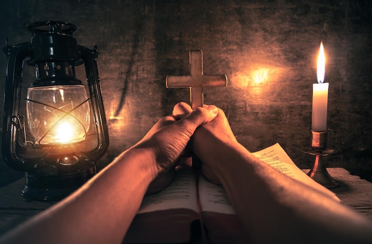 Photo cropped hands of person praying on bible and religious cross