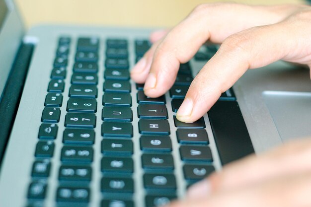 Photo cropped hands of person using laptop on wooden table