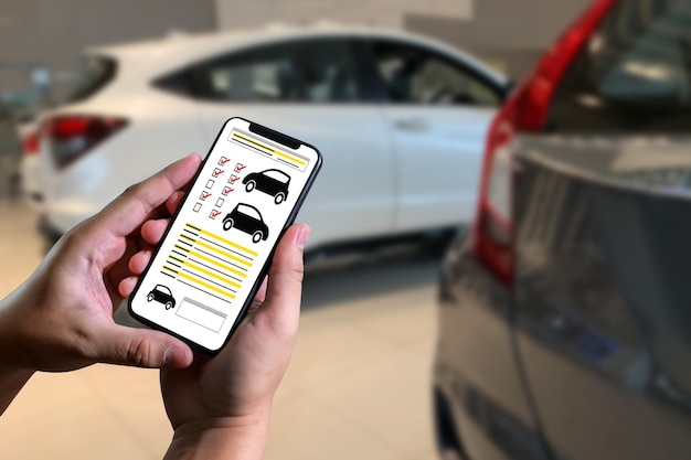 Cropped hands of person using mobile phone against cars
