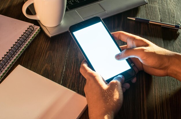 Photo cropped hands of person using mobile phone on table