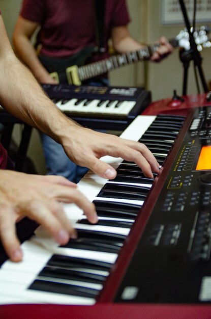 Foto mani tagliate che suonano il pianoforte da un uomo con la chitarra