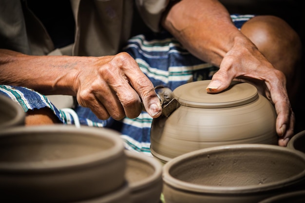 cropped hands of potter making clay pot at pottery