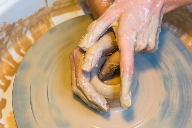 Photo cropped hands of potter molding clay