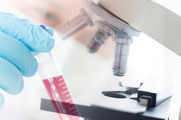 Photo cropped hands of scientist examining chemical with microscope