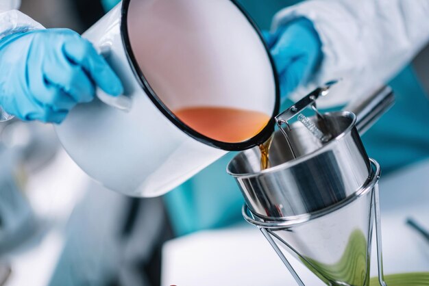 Foto mani tagliate di uno scienziato che versa liquido in un contenitore in laboratorio