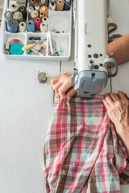 Photo cropped hands sewing textile on machine