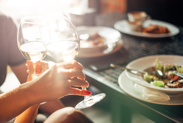 Photo cropped hands toasting wineglass by table