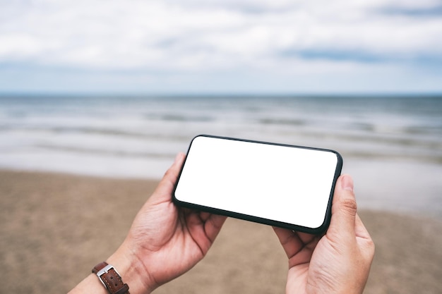 Photo cropped hands using blank phone at beach