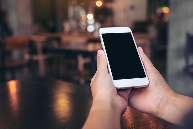 Cropped hands using smart phone at table in cafe