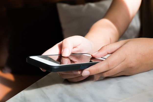 cropped hands using smart phone at table
