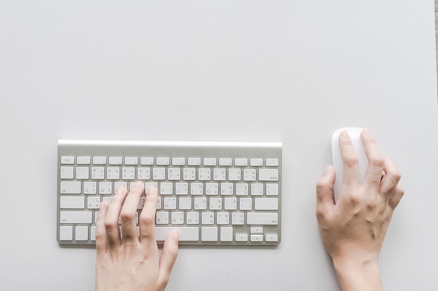 cropped hands using wireless keyboard and mouse on white desk