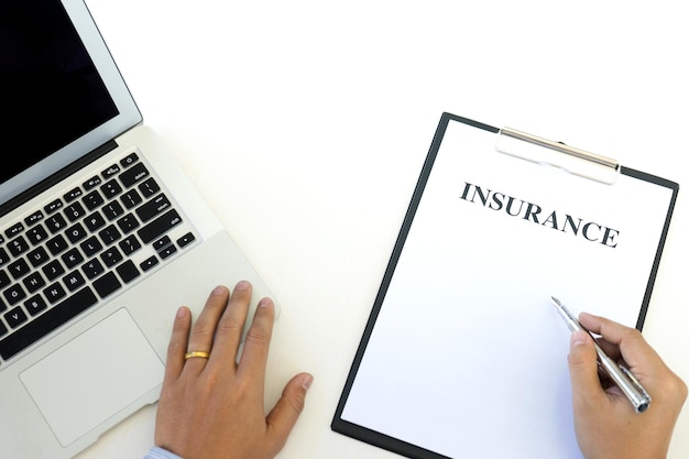 Photo cropped hands with insurance paper and laptop on desk