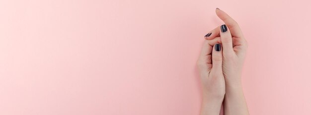 Cropped hands of woman against pink background