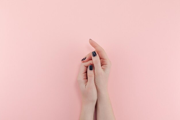 Cropped hands of woman against pink background