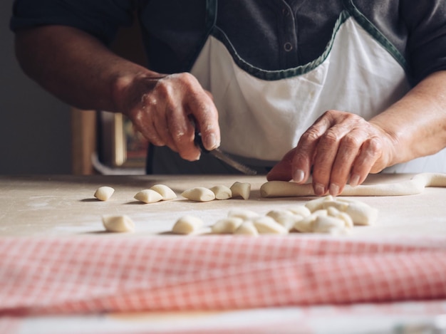 cropped hands of woman cutting dough in kitchen