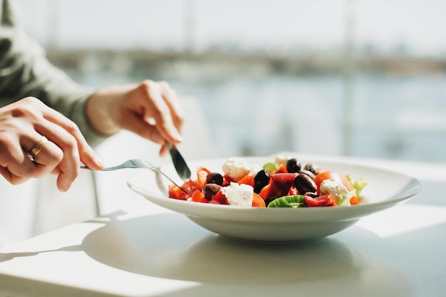 cropped hands of woman having salad in restaurant