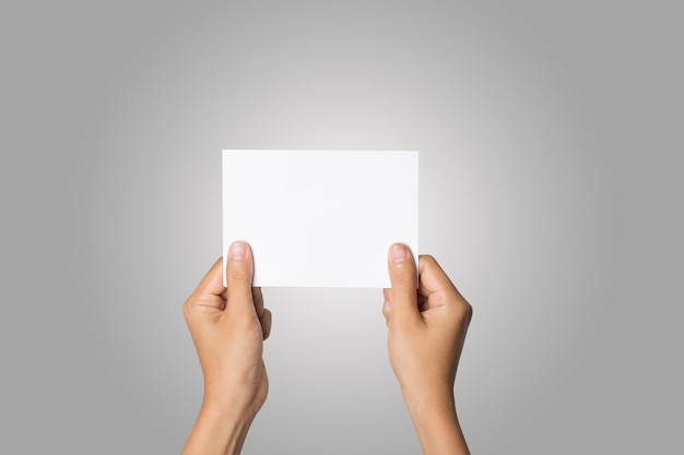 cropped hands of woman holding blank paper against gray background