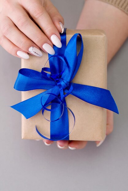 Cropped hands of woman holding gift box on gray background