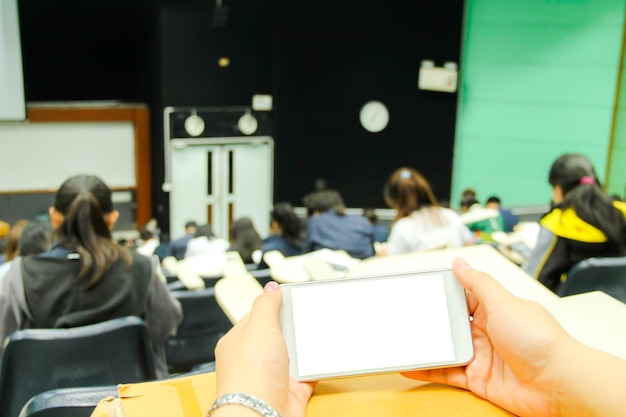 Foto mani tagliate di una donna che tiene uno smartphone in classe