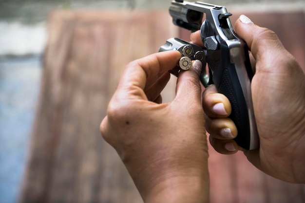 Foto mani tagliate di una donna che inserisce proiettili in una pistola