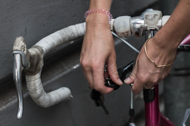 Foto mani tagliate di una donna che chiude la bicicletta contro il muro