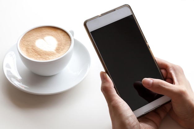 テーブルの上の携帯電話でカプチーノを撮影している女性の手を切った