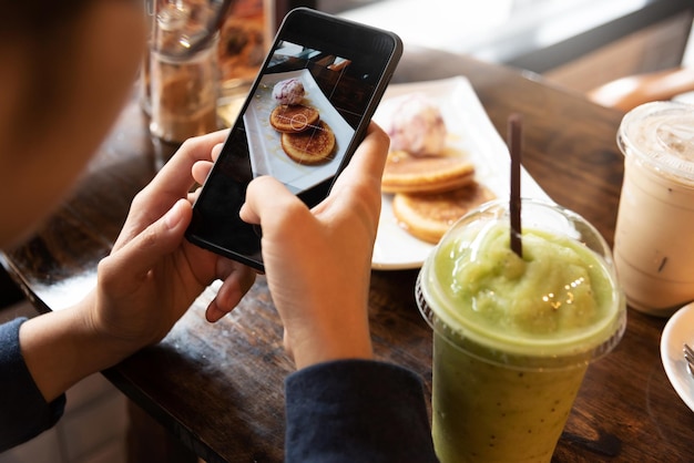 Cropped hands of woman photographing pancake in cafe