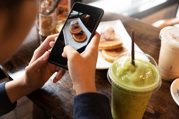 Photo cropped hands of woman photographing pancake in cafe