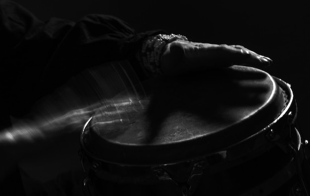 Cropped hands of woman playing drum in darkroom