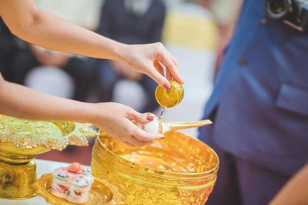 Cropped hands of woman pouring water on seashell