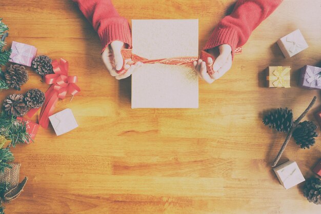 Photo cropped hands of woman tying christmas on table