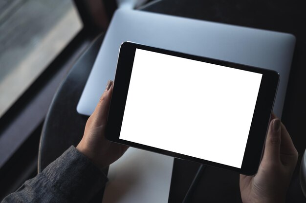 Foto mani tagliate di una donna che usa un tablet digitale vuoto al tavolo