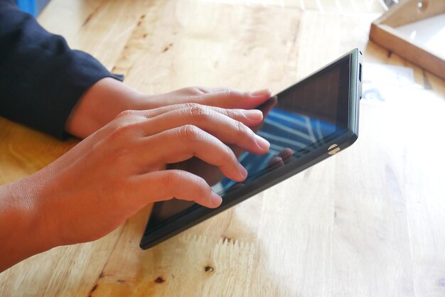 Photo cropped hands of woman using digital tablet at table