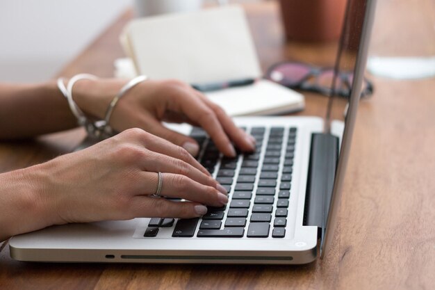 Cropped hands of woman using laptop in office