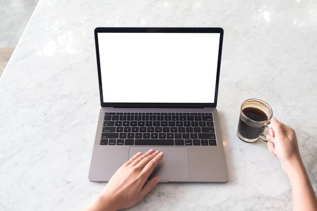 Photo cropped hands of woman using laptop on table in cafe