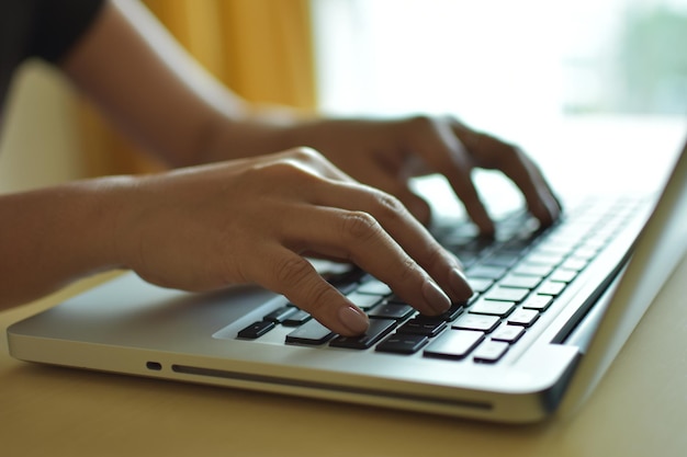 Photo cropped hands of woman using laptop on table