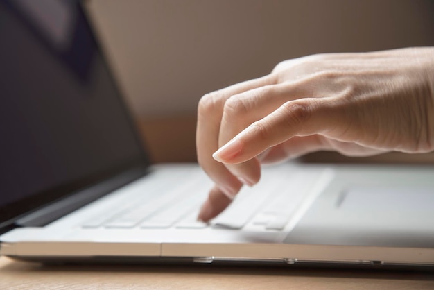 Cropped hands of woman using laptop on table