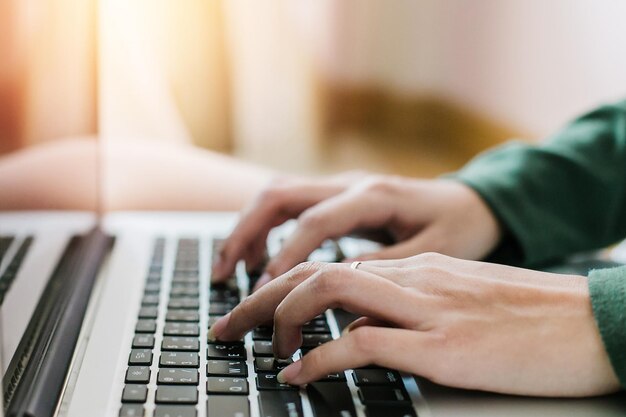 Photo cropped hands of woman using laptop