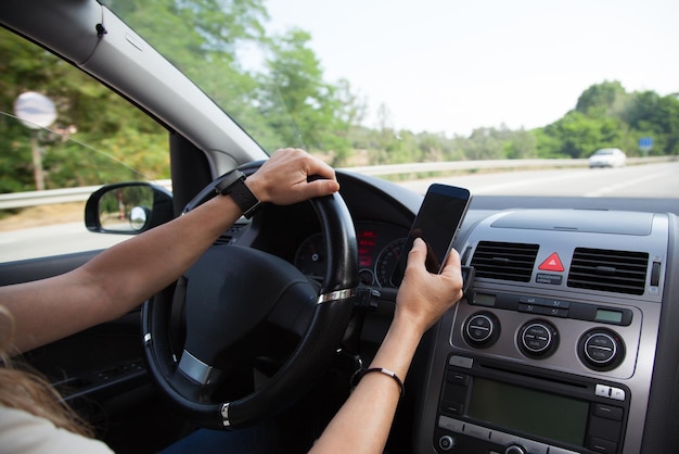 Cropped hands of woman using phone while driving car