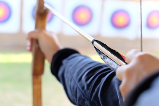 Photo cropped hands of woman with bow and arrow aiming at target