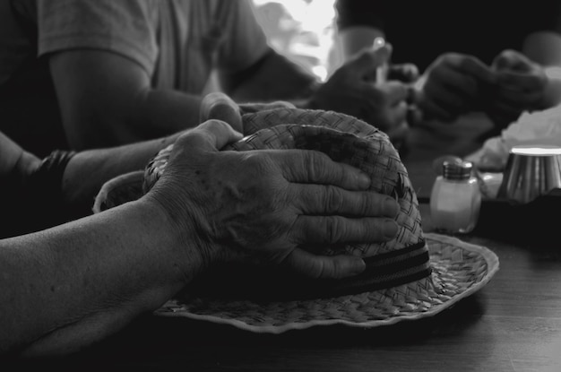 Photo cropped hands of woman with hat by friends at table