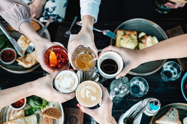 Photo cropped hands of women toasting drinking glasses at restaurant