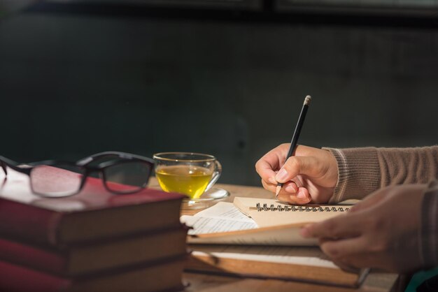 Photo cropped hands writing in book on table