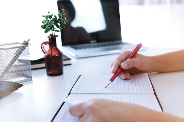 Cropped hands writing over diary in office