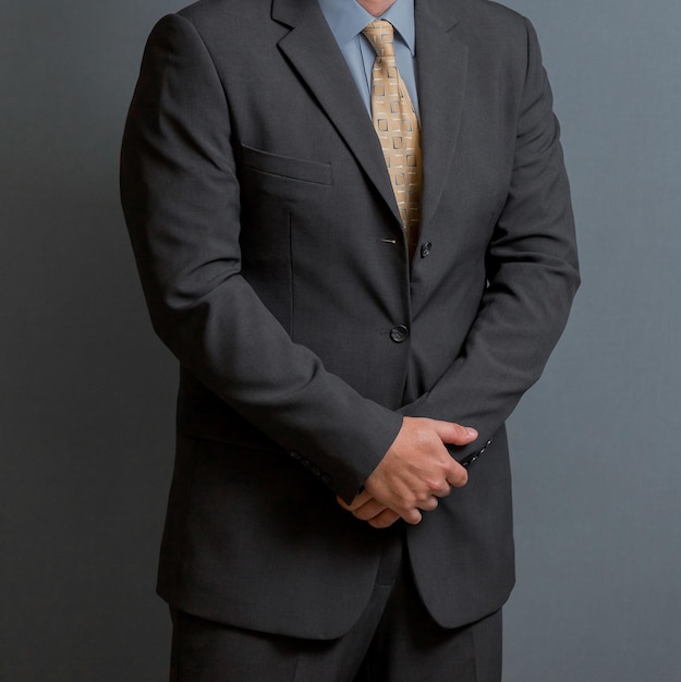 Cropped head Man standing in a smart suit with hands together