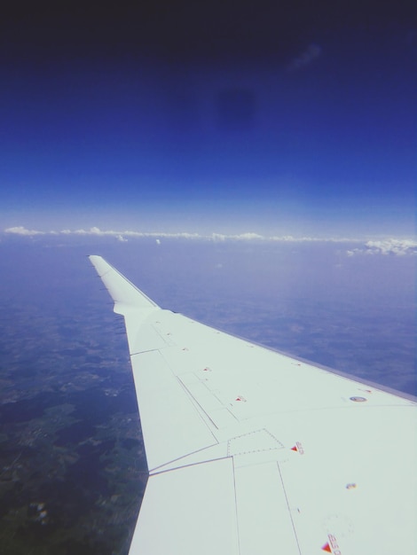 Photo cropped image of aircraft wing flying against sky